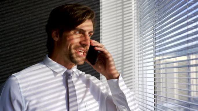 年轻的白人男性高管在现代办公室4k上用手机交谈的前视图