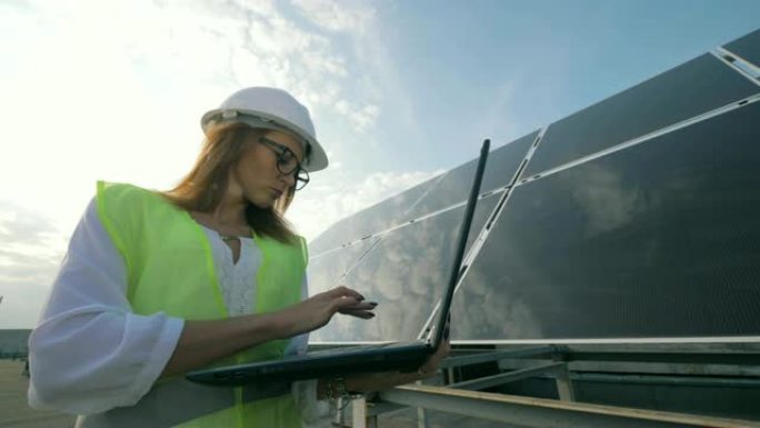 好看的女人在靠近太阳能建筑时正在操作笔记本电脑