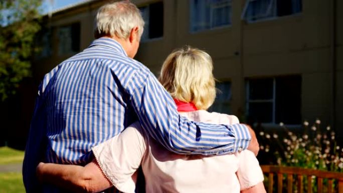活跃的高加索老年夫妇在养老院4k花园中互相拥抱的后视图
