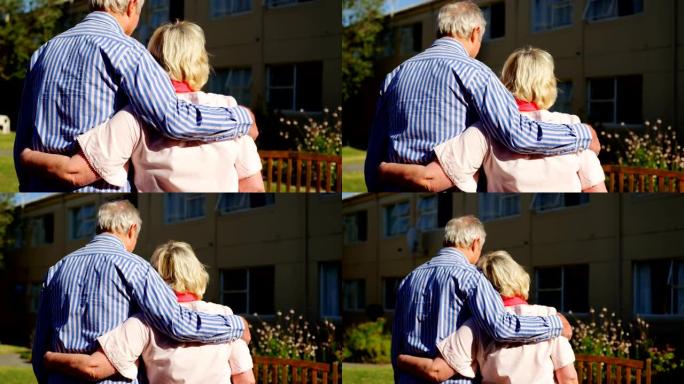 活跃的高加索老年夫妇在养老院4k花园中互相拥抱的后视图