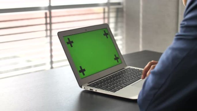 商人的手在笔记本电脑上的绿屏上工作