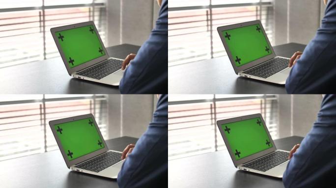商人的手在笔记本电脑上的绿屏上工作