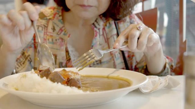 资深亚洲女性吃日本咖喱牛肉。