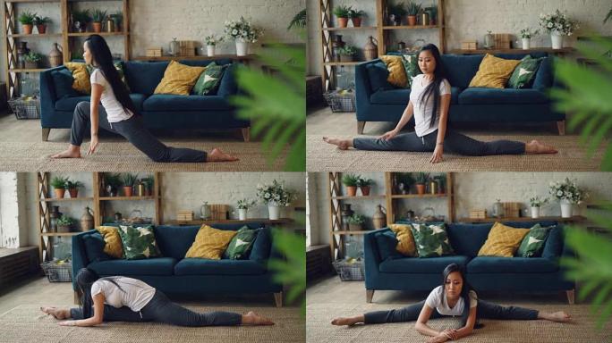 亚洲女体操运动员正在家里训练坐在客厅地毯上的劈腿。积极的生活方式，灵活性和运动的年轻人概念。