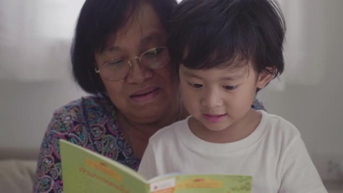 亚洲小男孩和祖父母在床上看书