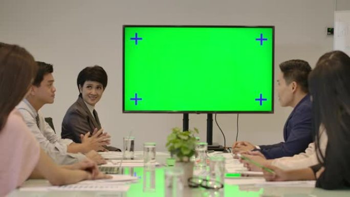 创意业务团队在会议室看着绿屏为发言人鼓掌。