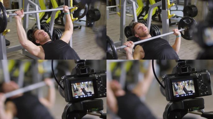 健身房教练在相机上显示躺着的杠铃卧推