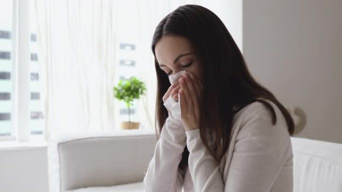 不健康的年轻女子有过敏性鼻炎在家吹鼻子