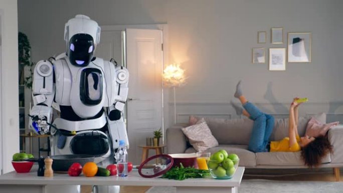 半机械人与人类概念。当一个女人用智能手机玩得开心时，白色机器人会做饭。