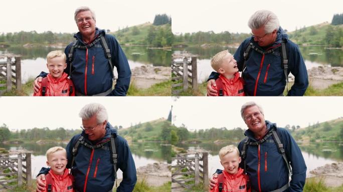 祖父和孙子笑着，站在湖岸，特写，英国湖区