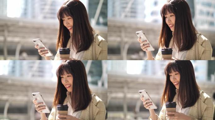 亚洲女性使用带咖啡杯的智能手机