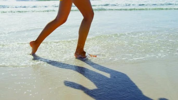 低矮的女人在海滩上散步时在海滩上泼水4k