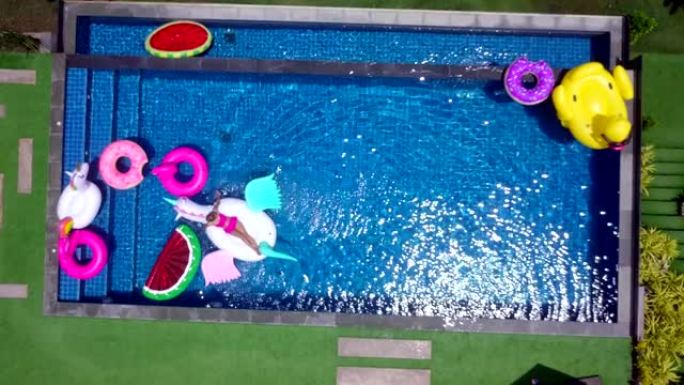 独角兽漂浮橡胶上穿着比基尼套装的女人的俯视图。在酒店或度假村度假时在游泳池享受放松时间