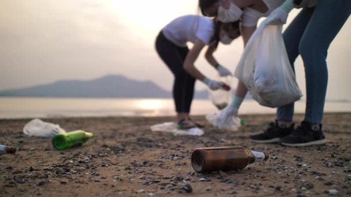 人们在海滩上捡起塑料瓶的特写镜头，慢动作，环境保护