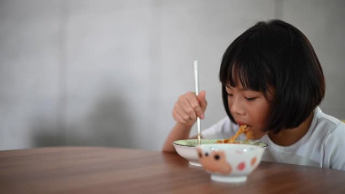 一个亚洲华人春天的年轻女孩在饭厅里家里用筷子吃意大利面