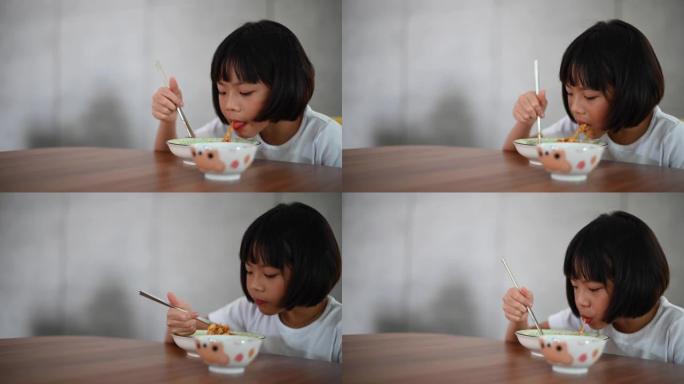 一个亚洲华人春天的年轻女孩在饭厅里家里用筷子吃意大利面