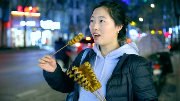 亚洲年轻女子晚上享受街头美食