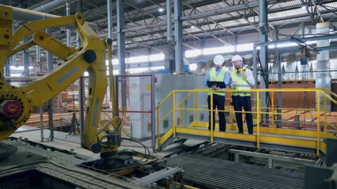 工厂工人正在管理现代机械臂的工作
