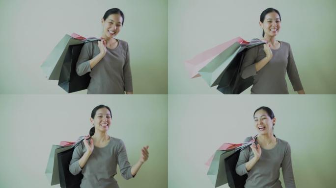 年轻快乐的亚洲女人拿着很多购物袋在白色背景上转身