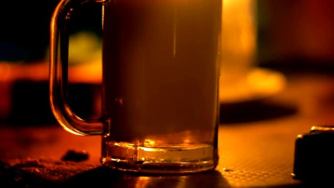 特写镜头，有人在休息室酒吧用温暖的烛光将起泡的苏打水饮料倒入桌子上的玻璃杯中。