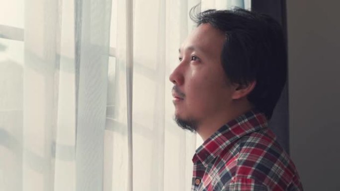 亚洲男子透过窗户自我检疫寻找冠状病毒