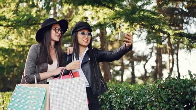 兴奋的女孩正在使用智能手机手持设备进行在线视频通话，并向购物袋展示购物。交流、技术和有趣的概念。