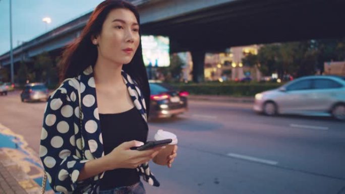 亚洲女商人晚上在城市街道上用智能手机发短信。