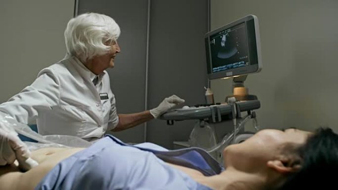 开朗的高级医生用超声仪检查病人