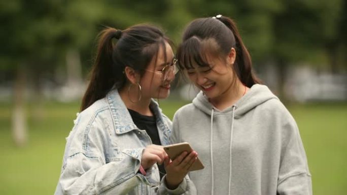 两名亚洲大学女生在校园里看手机