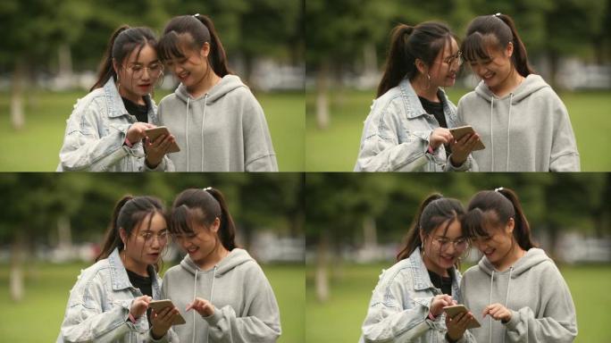 两名亚洲大学女生在校园里看手机
