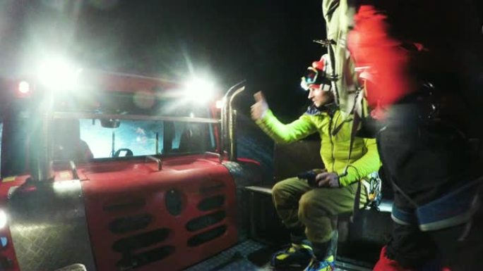 竖起大拇指。登山者在夜间在雪道美容师中骑行