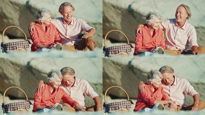 带着智能手机在海滩上微笑的高级夫妇