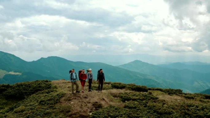 四个背着背包的人站在山上