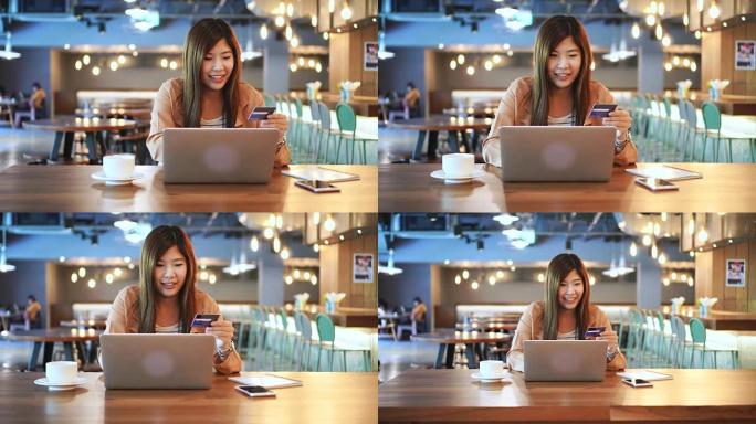 4k镜头亚洲妇女使用信用卡与笔记本电脑在共同工作空间，商务和在线支付概念进行在线交易的场景