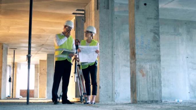 施工现场与两名建设者、建设者讨论蓝图。