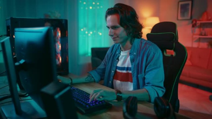 兴奋的玩家在他的个人电脑上玩在线视频游戏。房间和电脑有彩色温暖的霓虹灯。年轻人留着长发，笑容英俊。在
