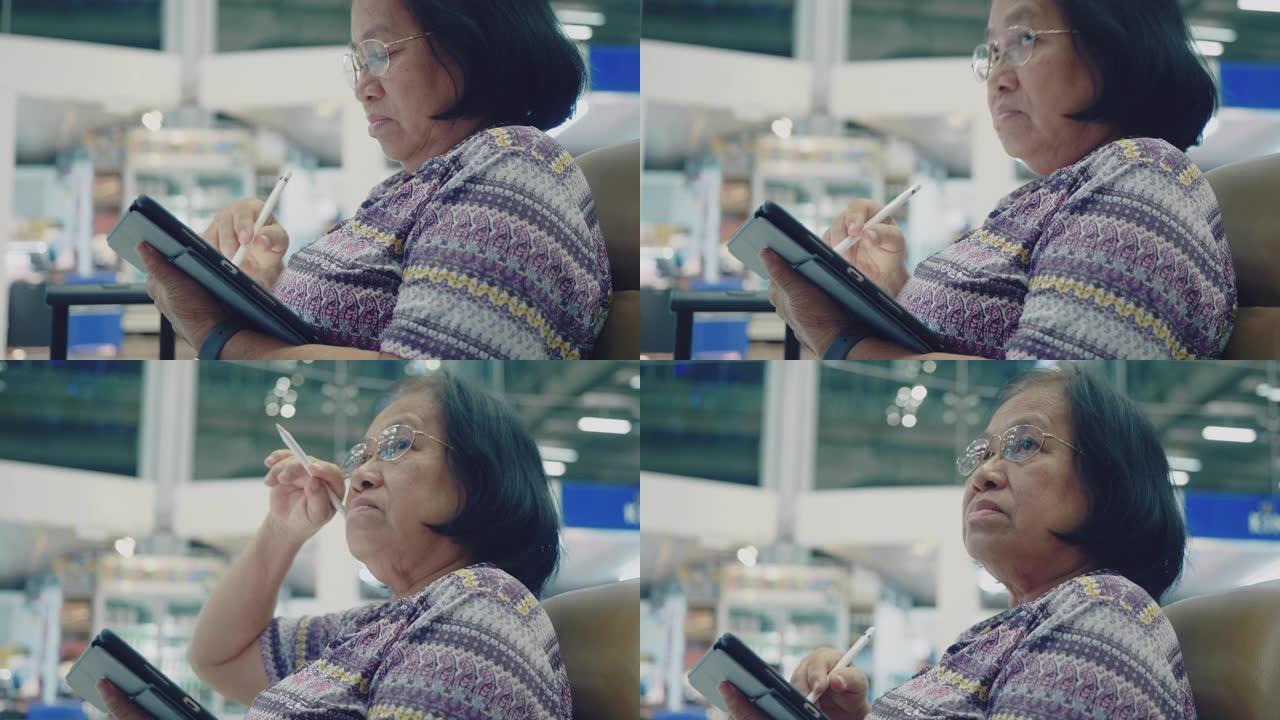祖母在机场候机室等候登机时使用平板电脑。