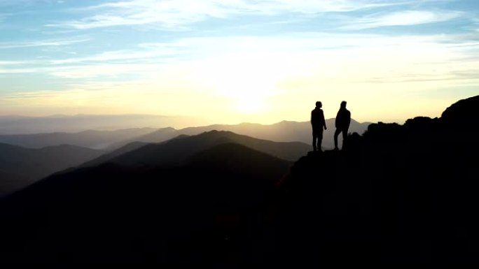这对夫妇站在山上，带着美丽的日落