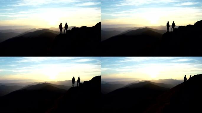 这对夫妇站在山上，带着美丽的日落