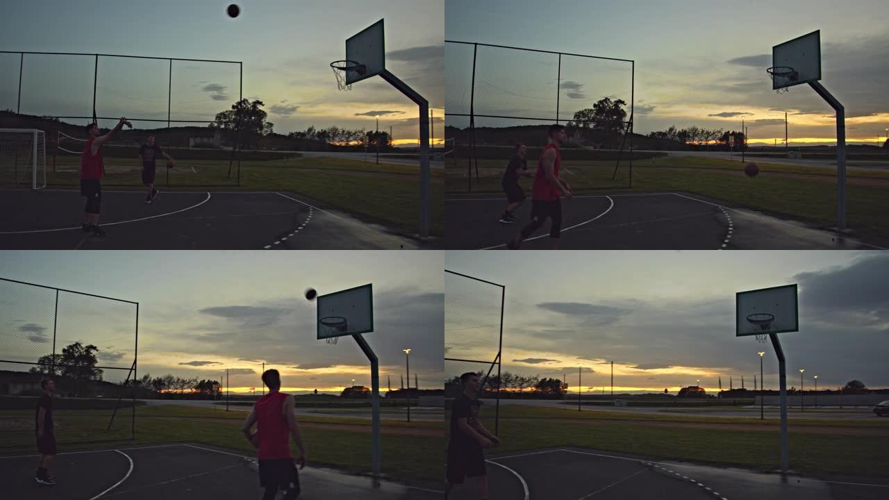 WS夫妇在黄昏时在室外篮球场打篮球。两个朋友打篮球。