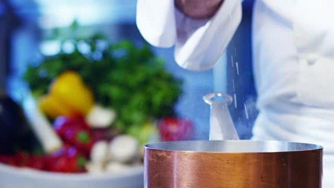 在意大利专业厨房中，厨师将盐倒在盘子或水中，以煮沸意大利面食的健康和清淡食品概念。