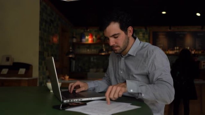 专注的商人在一家面包店工作，他的笔记本电脑上喝咖啡