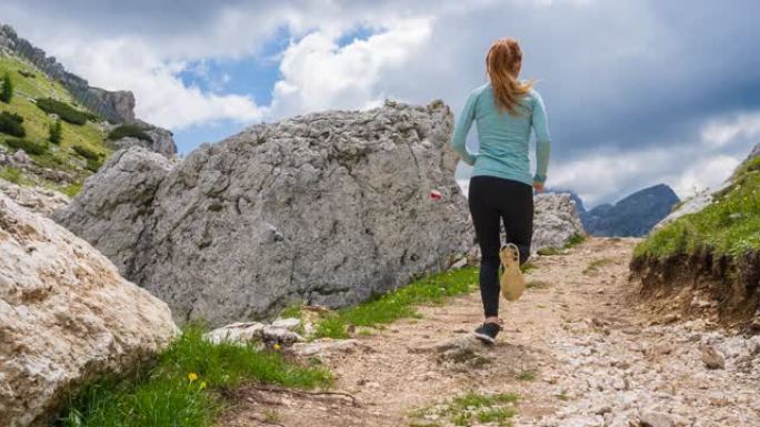 女跑步者在山区的岩石小径上奔跑
