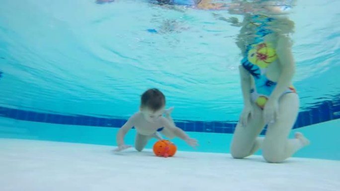 小男孩在母亲的帮助下从水下举起玩具