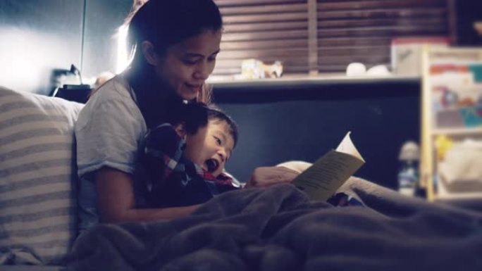 年轻的亚洲母亲读儿子的睡前故事