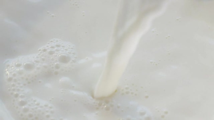 一只手在一个特殊的透明杯中慢动作倒入牛奶和早餐。