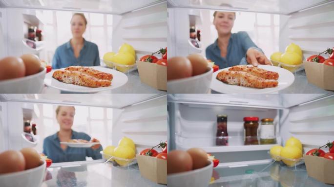 年轻女子将健康食品冰箱中的新鲜鲑鱼放在盘子里