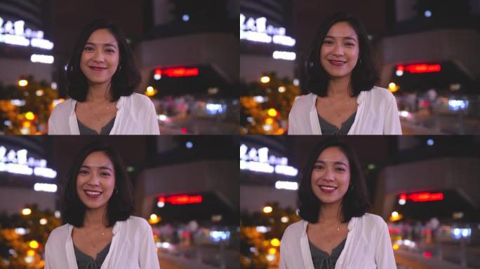 年轻漂亮的亚洲女人在4k的夏城之夜对着镜头微笑