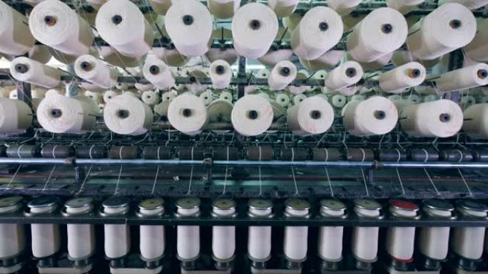 在纺织厂的带有线轴的工业机器上进行裁缝过程。