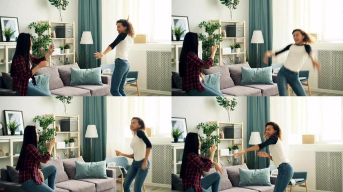 情绪激动的非裔美国女学生在家里笑着跳舞，玩得开心，而她的亚洲朋友正在用智能手机摄像头录制视频。青年和
